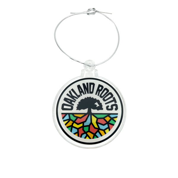Acrylic Oakland Roots crest ornament with silver string.