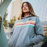 Model outside wearing gunmetal heather full zip hoodie with colored stripes and full-circle Roots SC mosaic logo on wearer's left the chest.