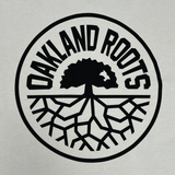 Detailed close-up of large black Oakland Roots SC logo print on a bone colored button-up baseball jersey.