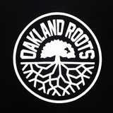 Detailed close-up of large white Oakland Roots SC logo print on a black button-up baseball jersey.