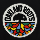 Close-up of large round full-color 3D Oakland Roots lagoon on the back of a black varsity jacket.